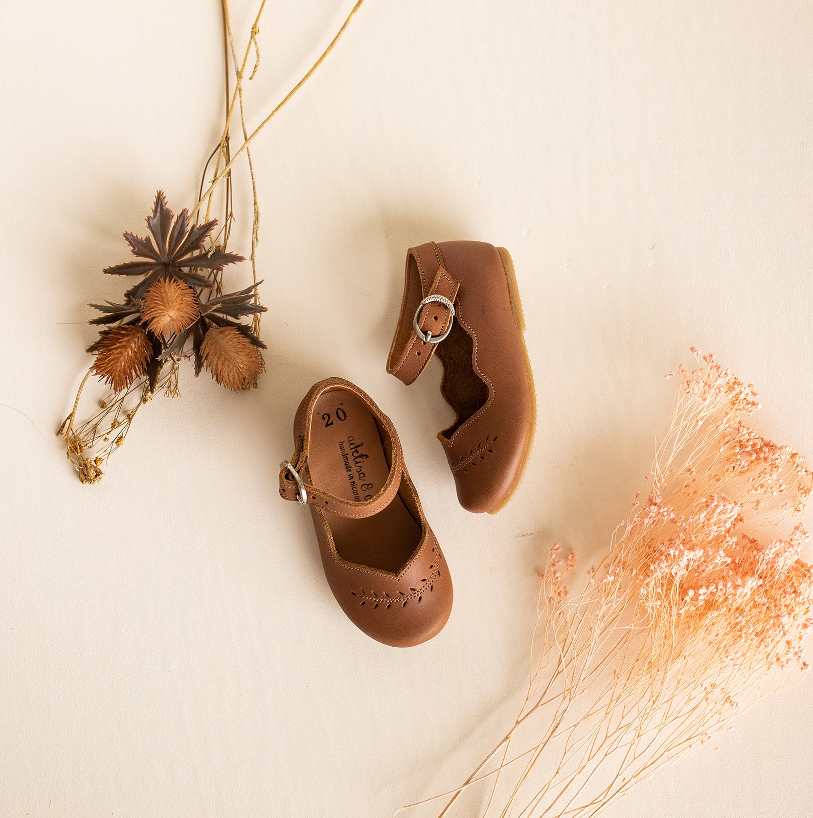 Adelisa &amp; Co handmade leather Mary Janes for girls featuring leaf detailing across the toe and scalloped edging. These Mary Jane leather shoes for girls come in a medium brown leather.