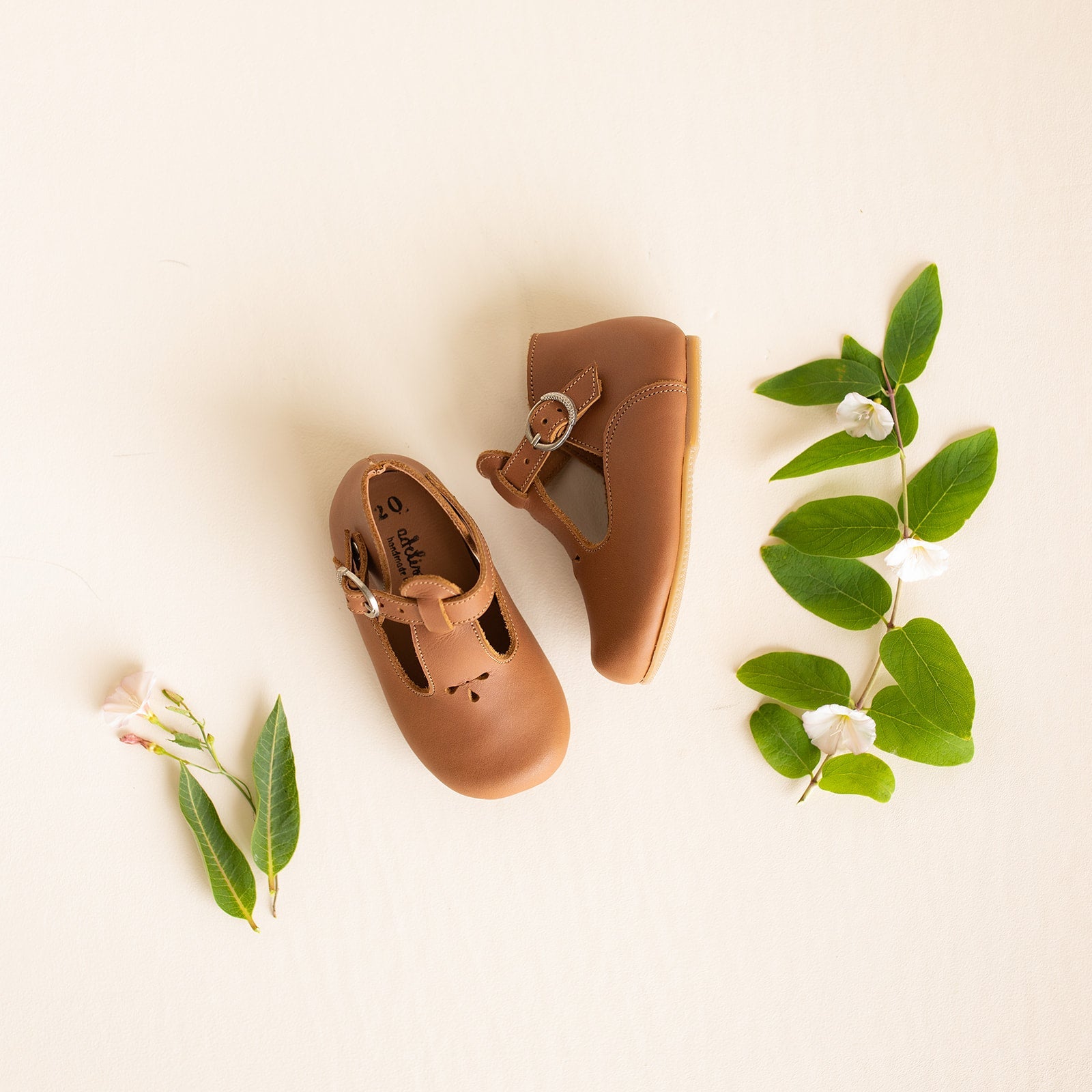 Medium brown leather Mary Janes for girls with floral detail.