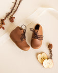 Adelisa & Co handmade leather Primavera boots in a medium brown tone. These leather children's boots feature beautiful scallop edging and subtle floral details.