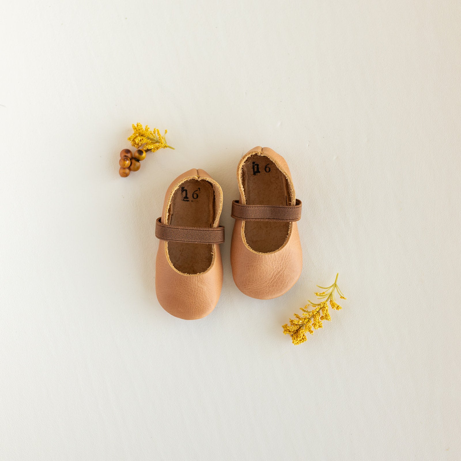 Slip on, soft sole baby Mary Jane with elastic band in a cognac leather.
