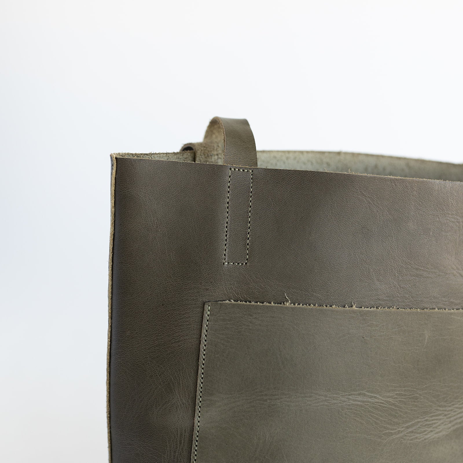 Small sized leather tote for children with a front pocket in an earthy, dark green leather.