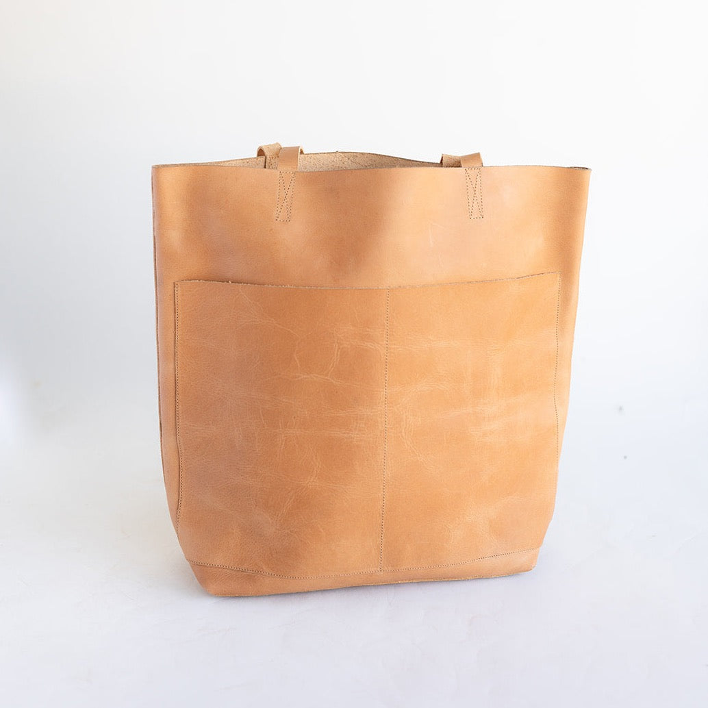 large women's leather tote bag in a cognac tone. Features to large pockets on the front and no hardware.