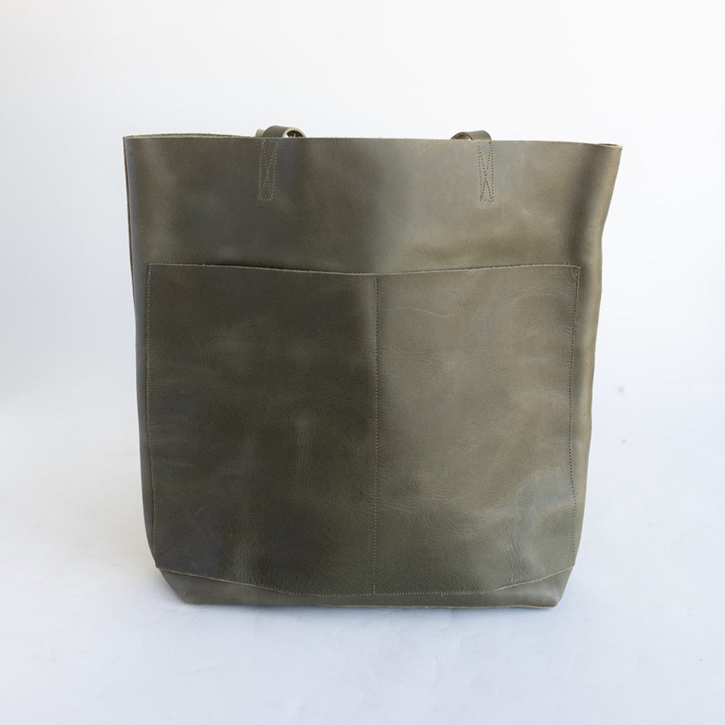 Large Women&#39;s leather tote with two front pockets and no hardware in an earthy, dark green leather.