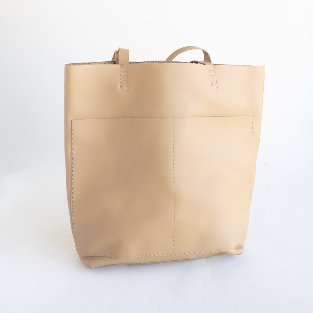 Large women&#39;s handmade leather tote in beige with two front pockets.