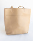 Large women's handmade leather tote in beige with two front pockets.