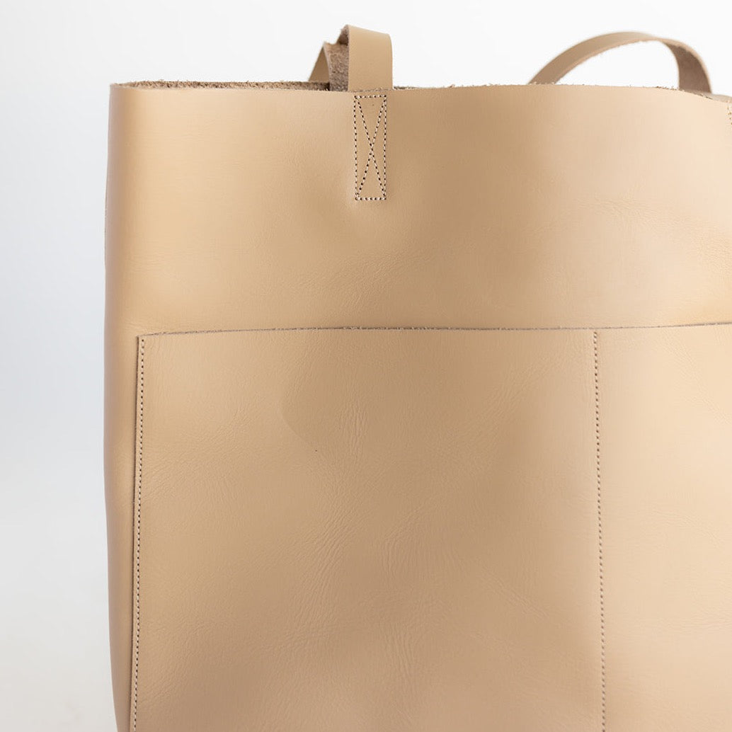 Large women&#39;s handmade leather tote in beige with two front pockets.